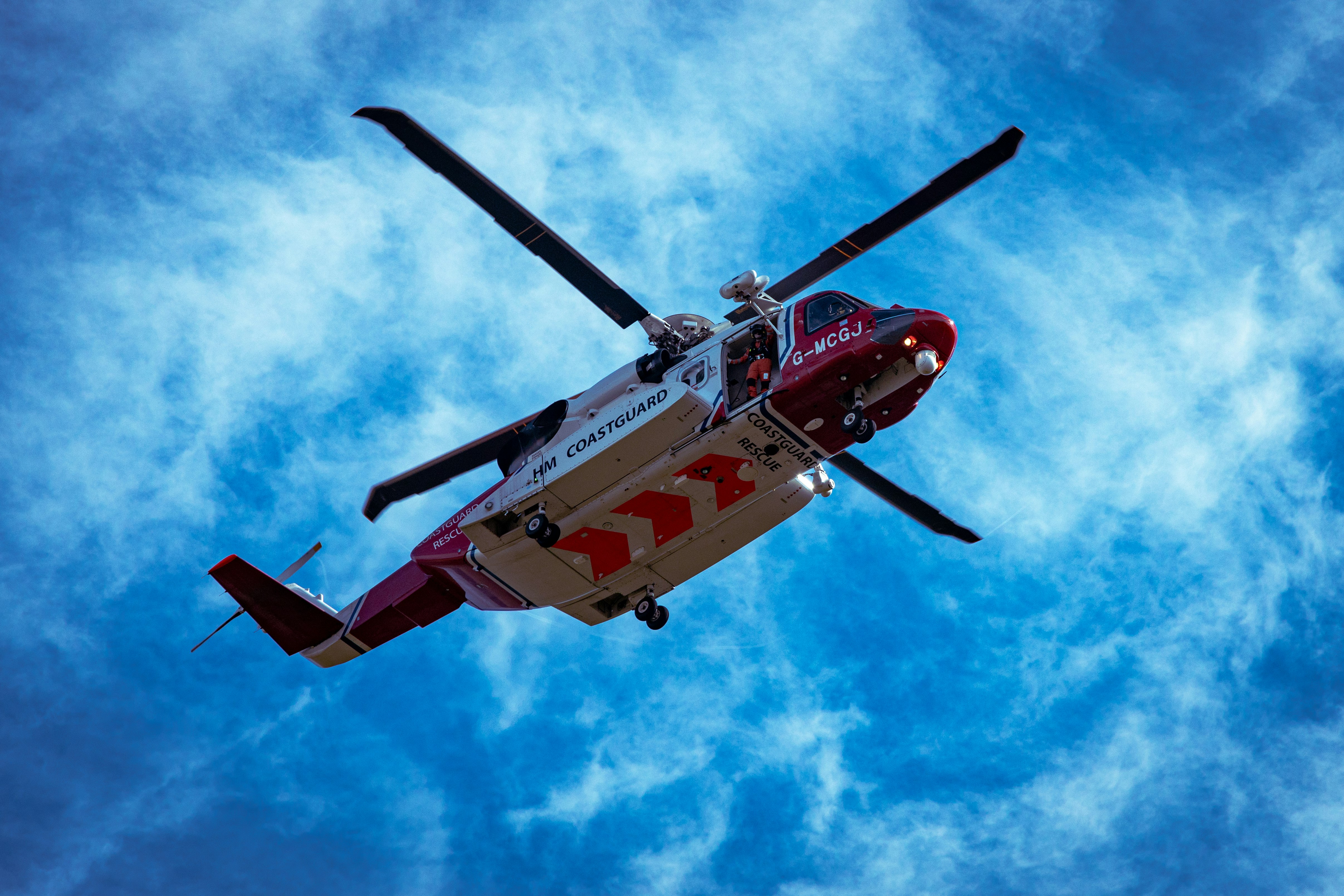 red and white helicopter flying in the sky